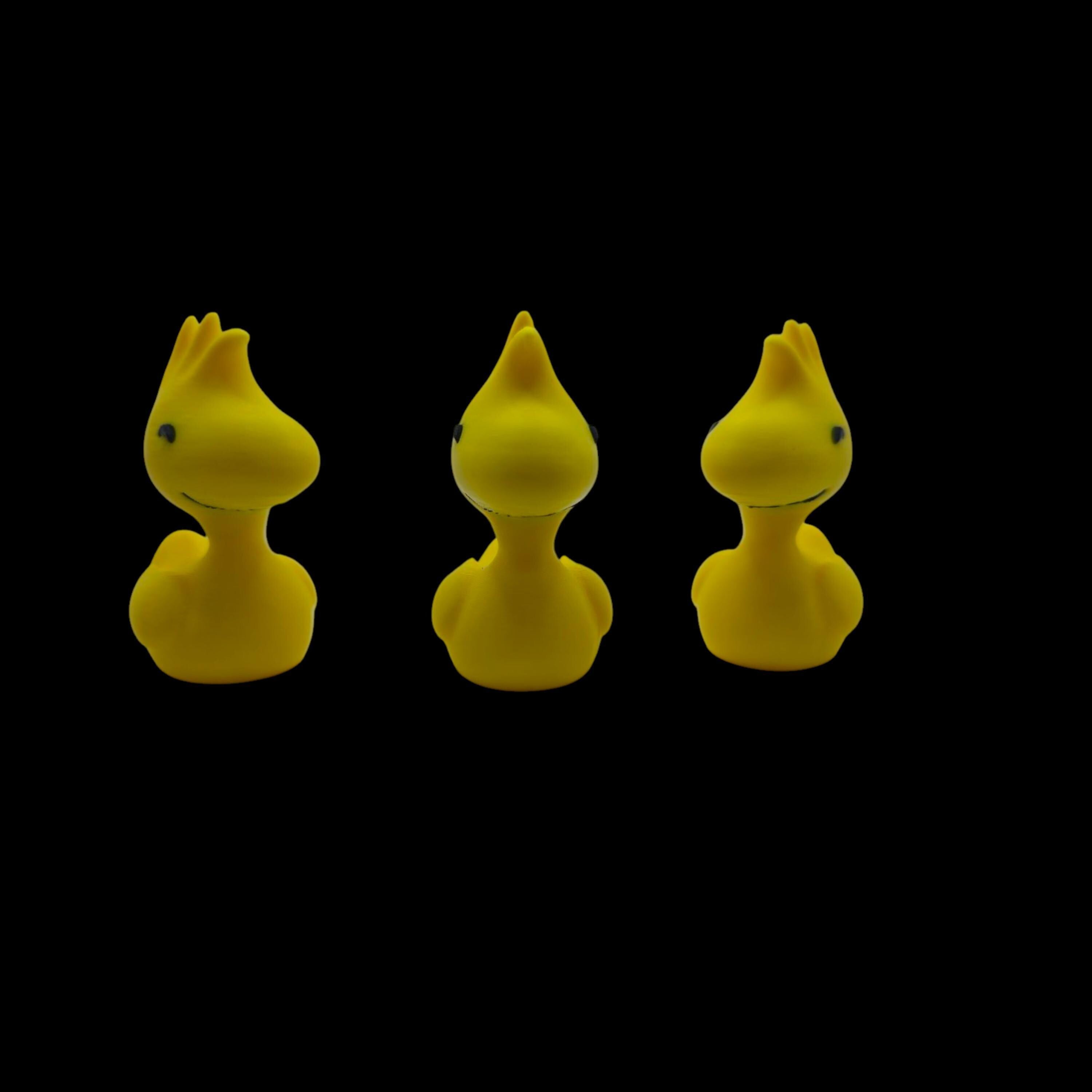 Three yellow Woodstock figurines in a row, each with spiky head feathers and two black dots for eyes, facing slightly left.