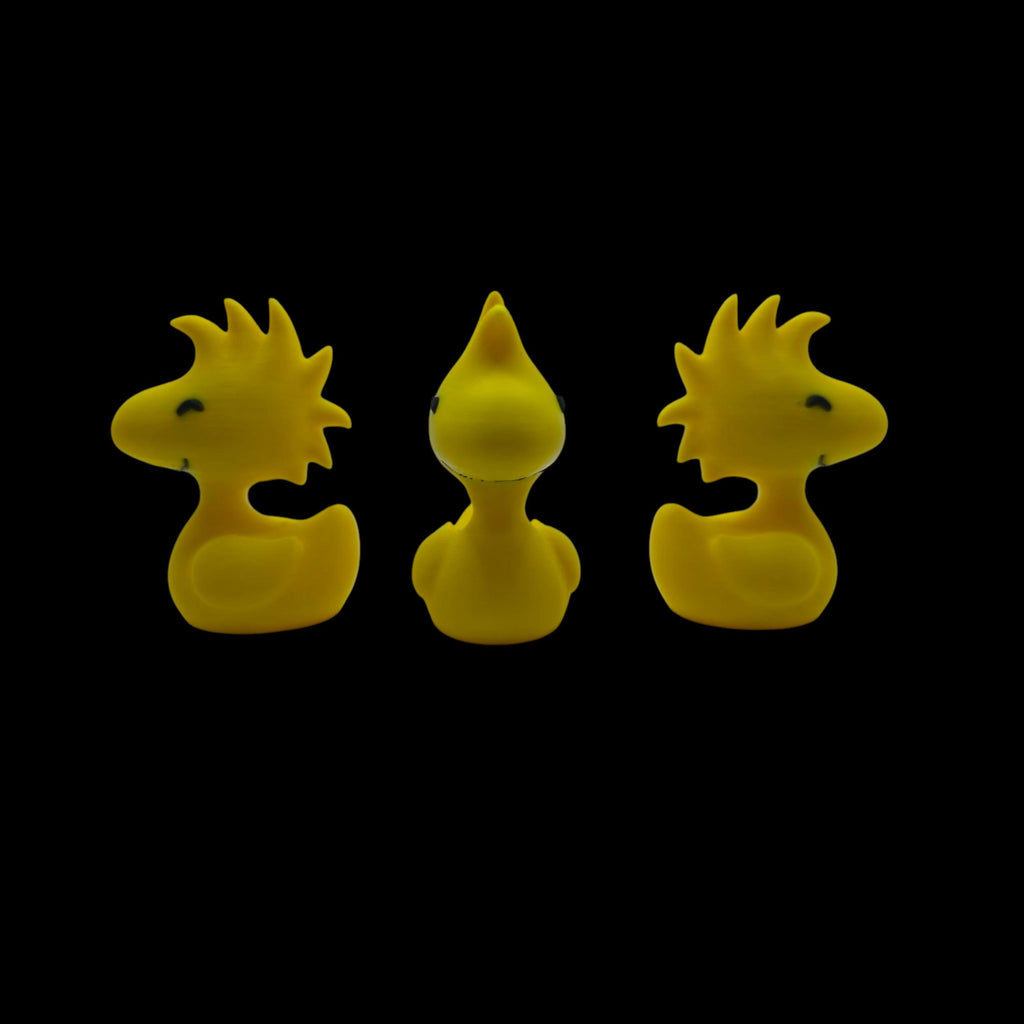 Three yellow Woodstock duck figurines are arranged in a row, with the center one facing forward and the outer two facing left and right, all against a black background.