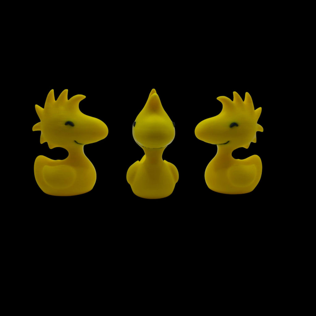 Three yellow Woodstock duck figurines are arranged in a row, with the center one facing forward and the outer two facing left and right, all against a black background.